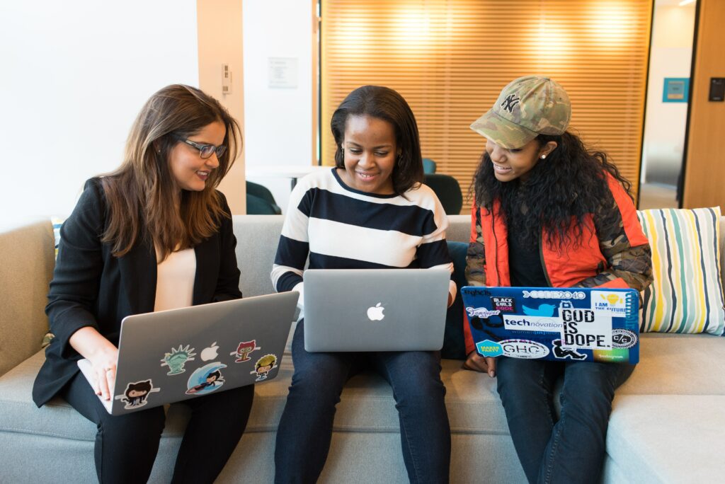 Three women professionals reviewing work on a laptop.