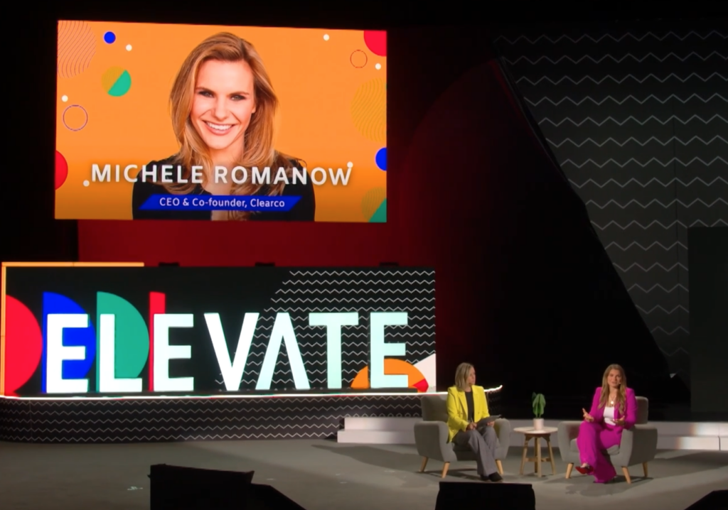 Two business women speaking on a stage at a conference. 